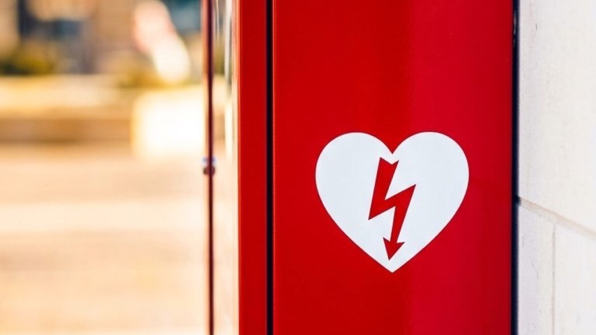 Verejne dostupný automatický externý defibrilátor (AED) v červenej skrinke na stene budovy